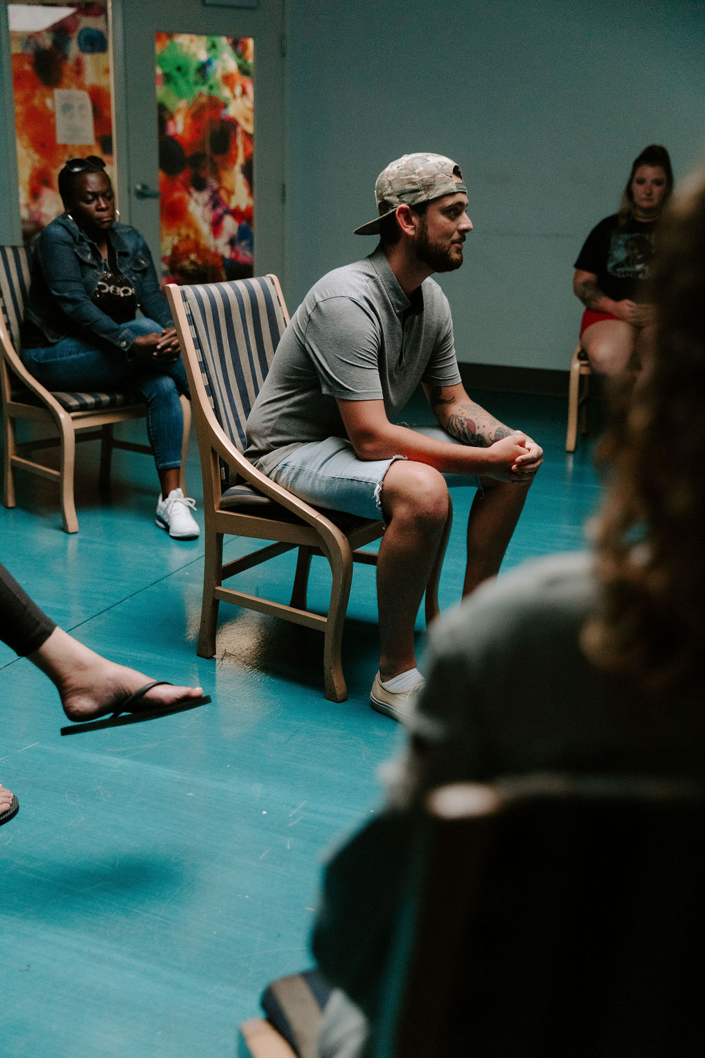 man speaking out in the center of group addiction therapy