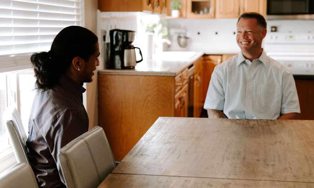 two men laughing in communal kitchen area of residential addiction recovery