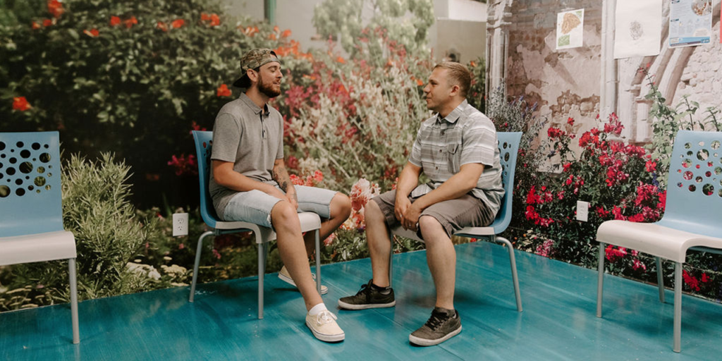 two men sitting outside of addiction recovery facility