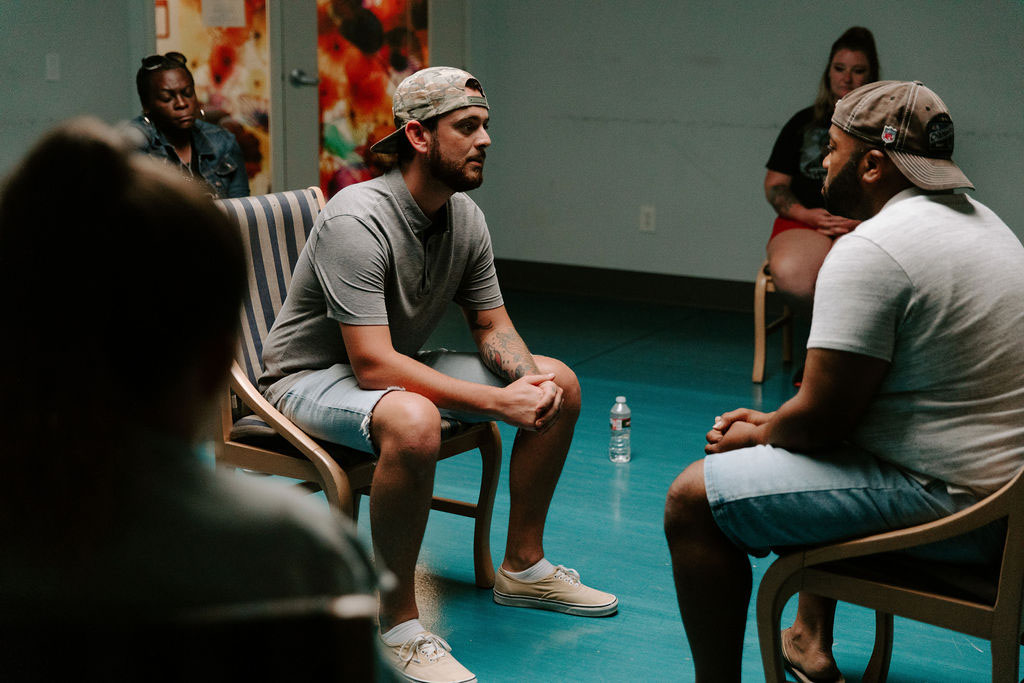 two men sitting in the middle of a circle in group therapy