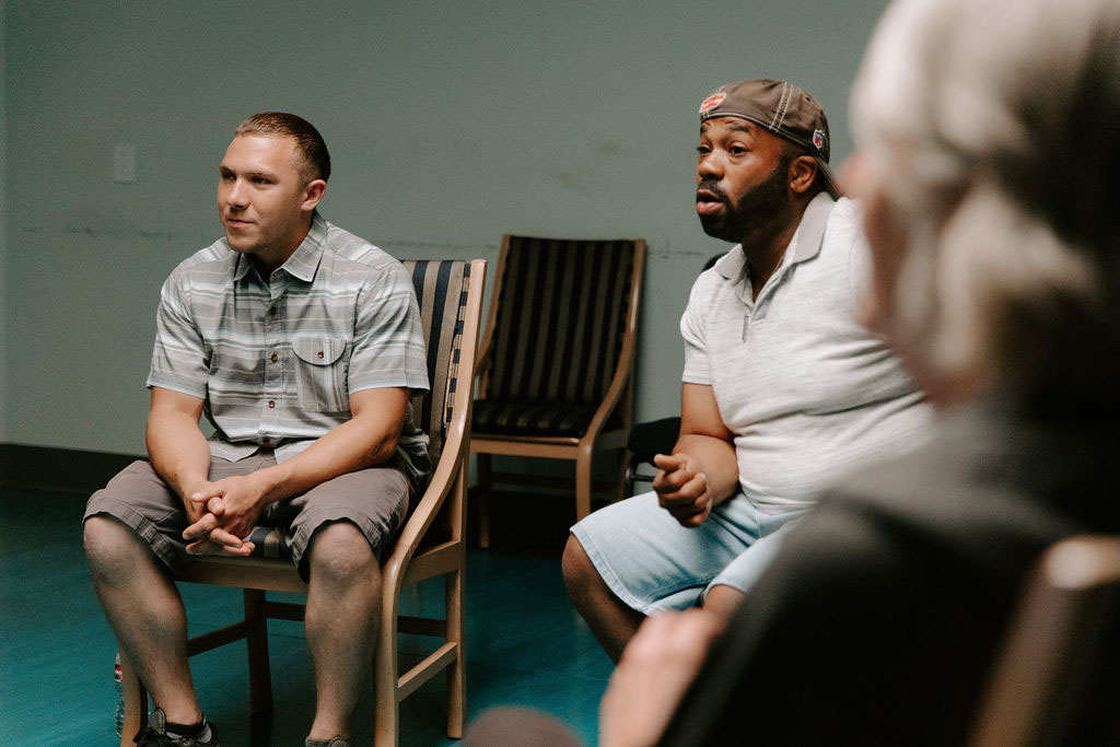 two men listening intently in addiction group therapy session
